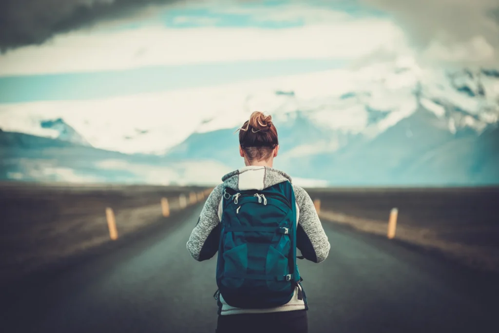 Mujer viajando y haciendo trekking sola con paisaje de montañas nevadas